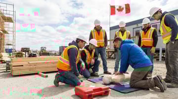 First aid CPR training on a Canadian construction site with workers in hard hats and hi-vis vests