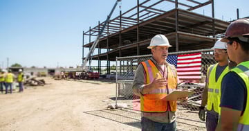 Construction foreman holding a clipboard and addressing workers during an OSHA toolbox talk on a US jobsite