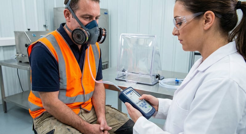 Technician conducting quantitative respirator fit test on a construction worker wearing a half-face P100 respirator