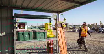 Well-organized construction site first aid station with AED, eye wash, first aid kits, and emergency equipment under a shelter